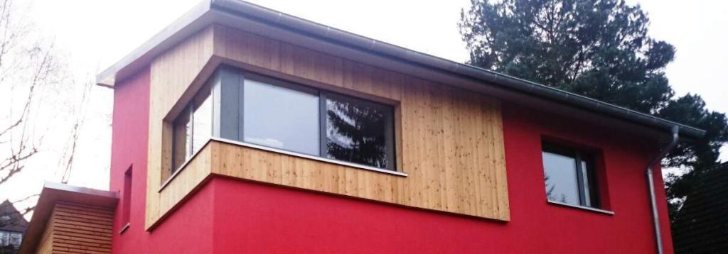 Ein rotes Passivhaus mit Pultdach, Unilux-Fenster und einer Holzfassade
